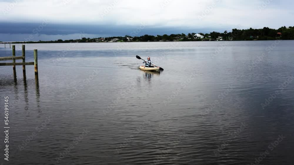 An elderly man (60 years old) kayaks down a river in Florida after fishing to escape the approaching rain An elderly man (60 years old) kayaks down a river in Florida after fishing to escape the approaching rain