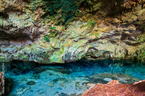 View of beautiful natural pool of crystal clear water formed in a rocky cave with stalagmites and stalagmites. Kuza cave in Zanzibar, Tanzania