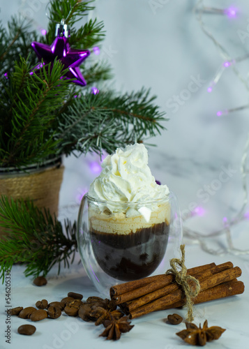 Homemade delicious spicy hot chocolate with whipped cream. Christmas hot chocolate with whipped cream with spices and Christmas tree twigs. A cozy Christmas drink.  Selective focus. 