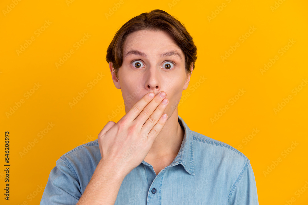 Young man isolated on yellow color background covering mouth with hand telling private news Young man isolated on yellow color background covering mouth with hand telling private news