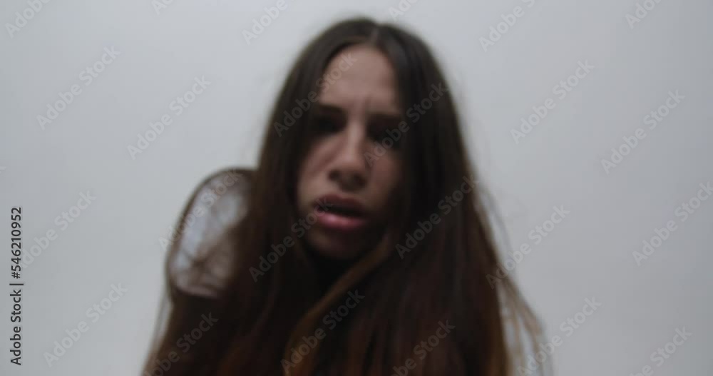 Extreme close up of teenager girl with long red hair, dressed in straitjacket, barefoot, tied with straps, sits in the corner of Ward in mental hospital.exacerbation of schizophrenia Extreme close up of teenager girl with long red hair, dressed in straitjacket, barefoot, tied with straps, sits in the corner of Ward in mental hospital.exacerbation of schizophrenia