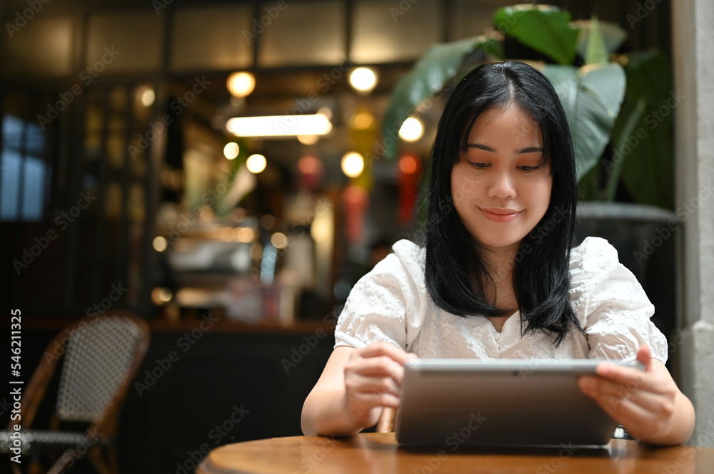 Asian female using tablet while relaxing in the coffee shop. freelance remote working Asian female using tablet while relaxing in the coffee shop. freelance remote working