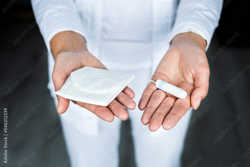 gynecologist holds a tampon and a pad in his hands close-up 