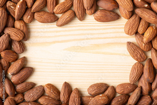 Frame made of almonds on wooden table. Almond nuts around on wooden background, fresh tasty nuts