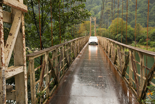 Beautiful view on rusty metal bridge over river and car in mountains