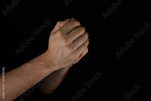 Man praying against black background, closeup view
