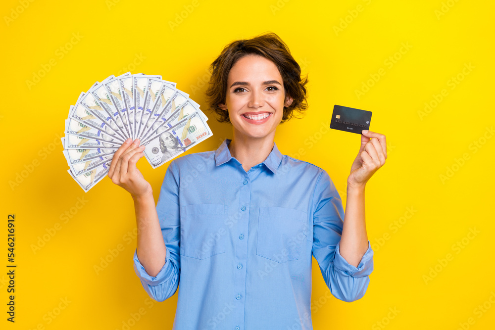 Photo of lovely nice girl with bob hairdo dressed blue shirt hold credit card money online shopping isolated on yellow color background Photo of lovely nice girl with bob hairdo dressed blue shirt hold credit card money online shopping isolated on yellow color background