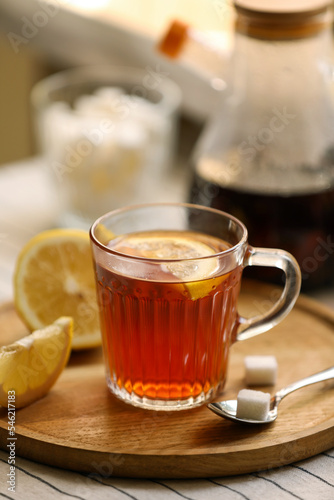Glass mug of aromatic tea with lemon and sugar on table, closeup