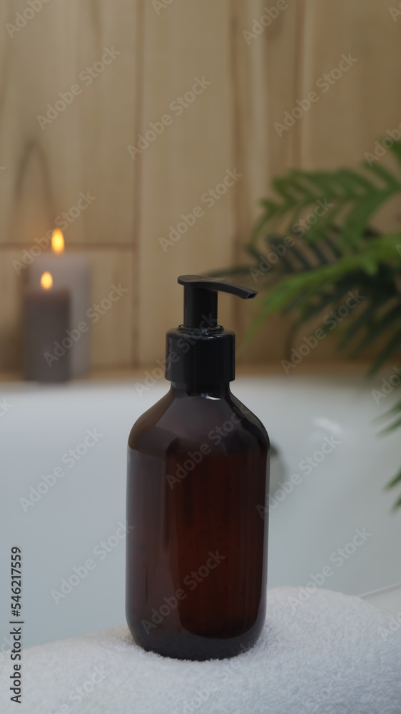 Black bottle of bubble bath and candles on tub indoors Black bottle of bubble bath and candles on tub indoors