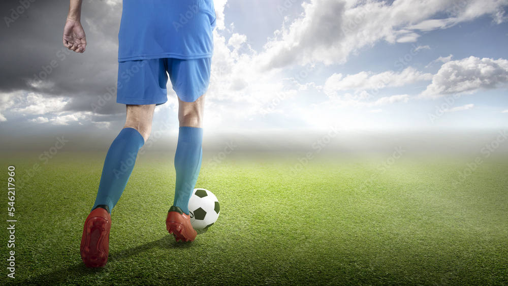 Rear view of a football player man in a blue jersey dribbling the ball Rear view of a football player man in a blue jersey dribbling the ball
