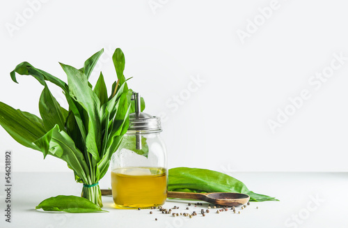 Wild garlic bunch on table with olive oil, seasoning and spoon. Seasonal healthy cooking concept