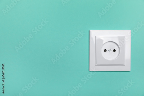 Power socket on turquoise wall, space for text. Electrical supply