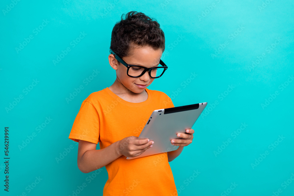 Photo of clever funky little guy dressed orange t-shirt arm typing modern gadget empty space isolated teal color background Photo of clever funky little guy dressed orange t-shirt arm typing modern gadget empty space isolated teal color background