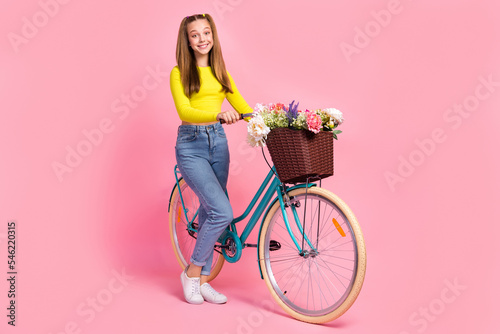 Full length photo of pretty shiny school girl dressed yellow crop top walking bicycle having rest isolated pink color background © deagreez