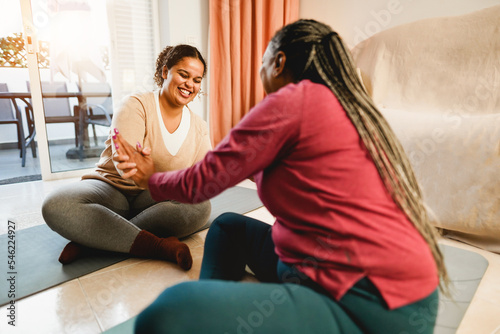 Mother and daughter doing fitness exercises at home together - Family and sport concept during winter time - Focus on girl face
