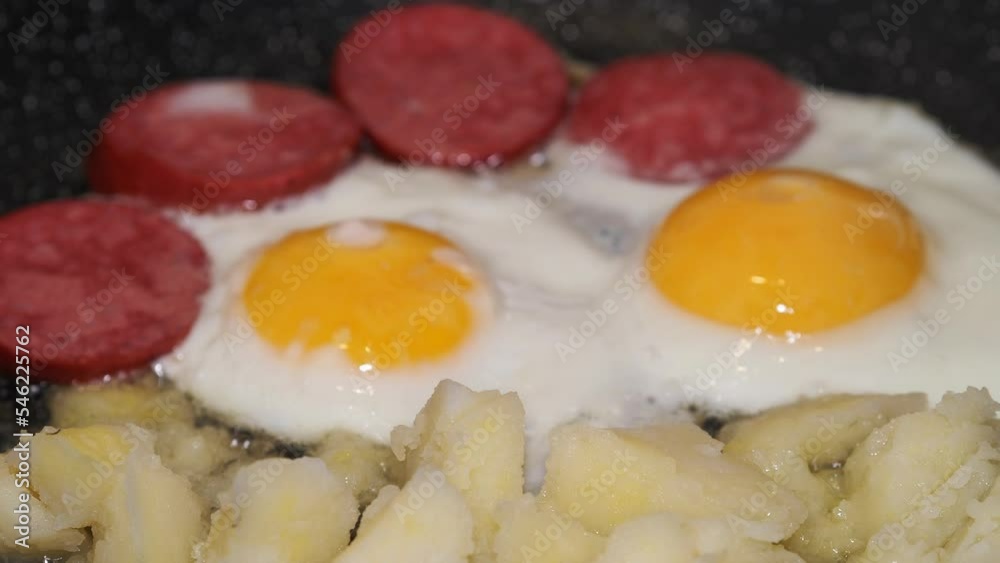 Simple food. Potatoes with sausage and eggs are fried in a frying pan. The camera is moving. Simple food. Potatoes with sausage and eggs are fried in a frying pan. The camera is moving.