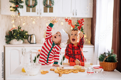 a happy family of cheerful kids cooks dough, bakes cookies in the kitchen. The concept of celebration and comfort