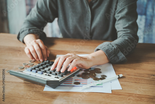 Midsection woman calculating about money with financial documents on the wooden table in the house. Concept of working from home. Financial planning, savings, investments, returns.
