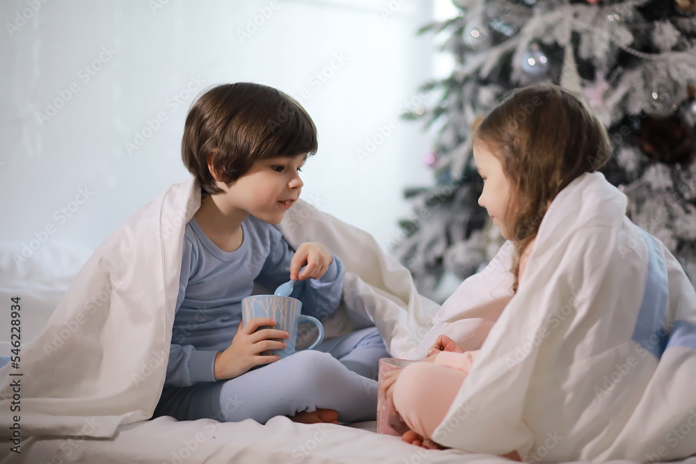 A family with children having fun on the bed under the covers during the Christmas holidays.