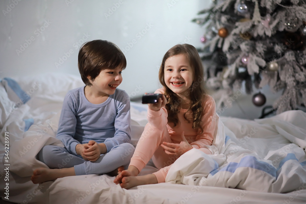 A family with children having fun on the bed under the covers during the Christmas holidays.