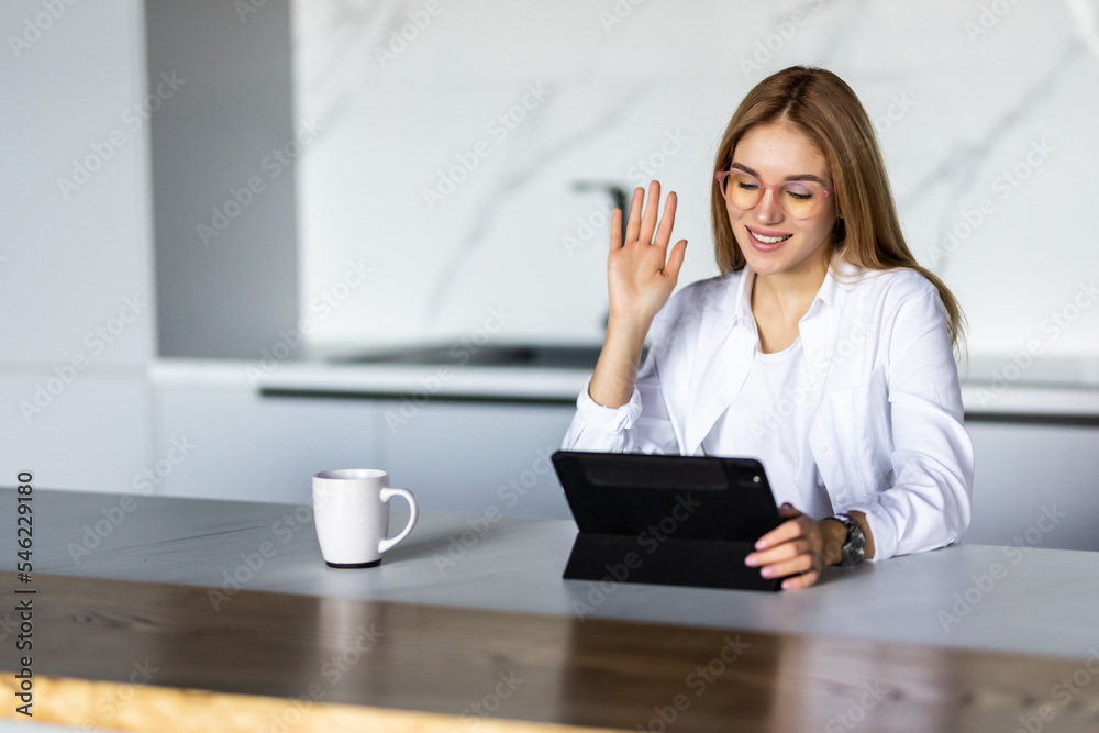 Young woman in the kitchen is drinking coffee and talking on a video call Young woman in the kitchen is drinking coffee and talking on a video call