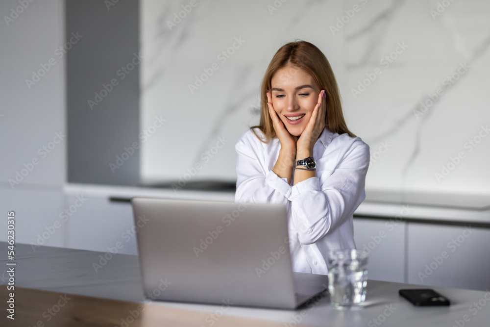 Happy young woman in the kitchen reading he news on her laptop Happy young woman in the kitchen reading he news on her laptop