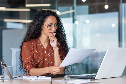 Successful satisfied and happy business woman working inside modern office, hispanic woman in glasses and shirt using laptop at work, photo