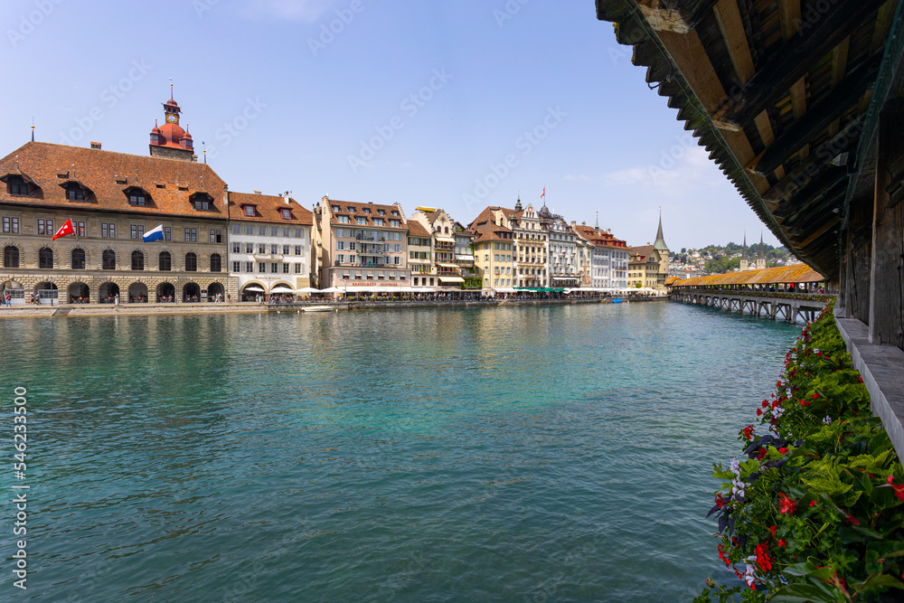 LUCERNE, SWITZERLAND, JUNE 21, 2022 - View of the wodden covered Kapellbrucke Bridge on the Reuss river and buildings in city center of Lucerne, Switzerland