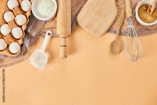 Bakery or cooking frame, ingredients, kitchen items for pastry on pastel orange background. Top view, copy space.