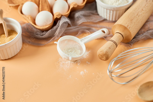 Bakery or cooking frame, ingredients, kitchen items for pastry on pastel orange background. Top view, copy space.