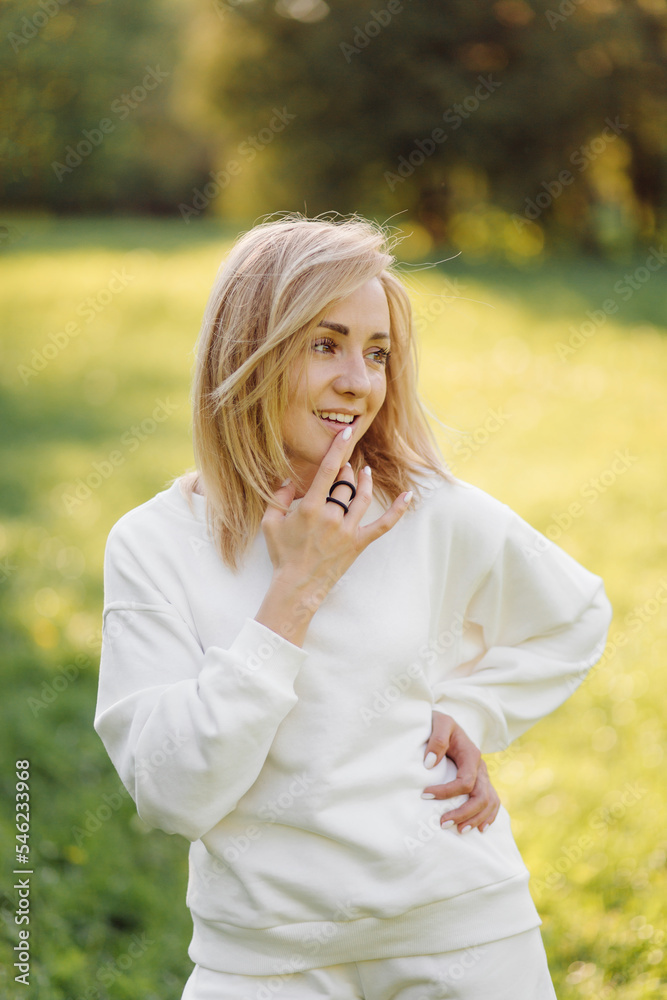 Young blonde girl is wearing a white hoodie smiling and walking in the woods Young blonde girl is wearing a white hoodie smiling and walking in the woods