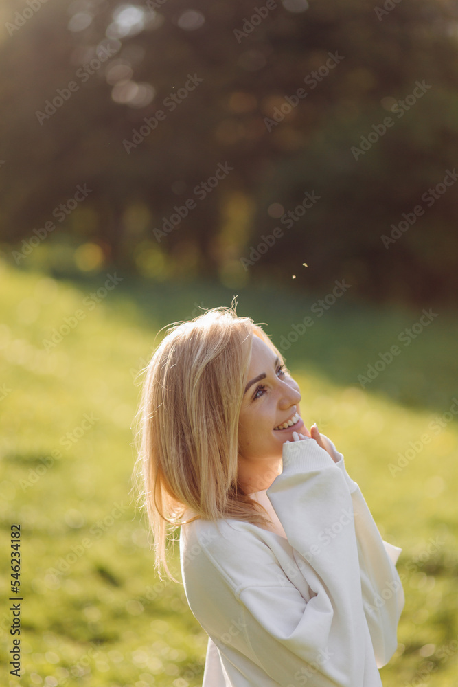 Young blonde girl is wearing a white hoodie smiling and walking in the woods Young blonde girl is wearing a white hoodie smiling and walking in the woods