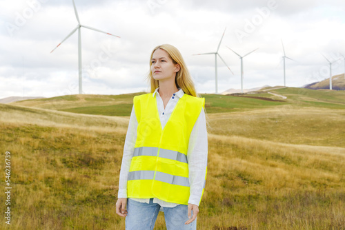 A young woman is an engineer of power systems against the background of wind turbines. Green Economy