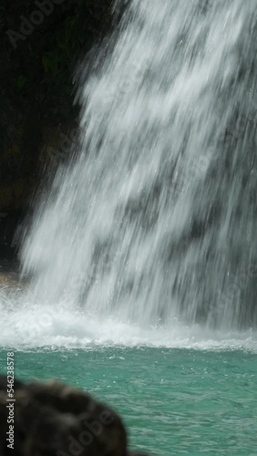 Panning close up footage of water falling on a pool at a waterfalls, vertical