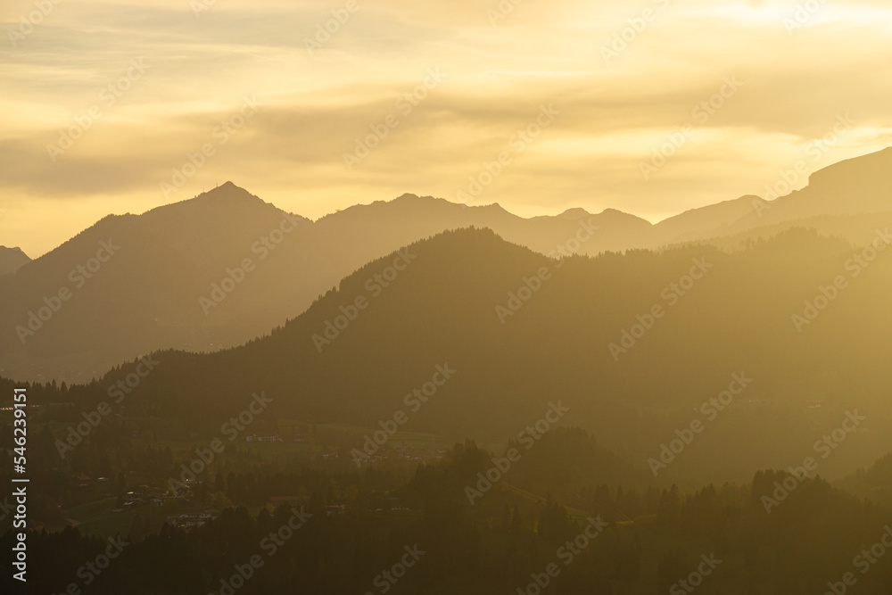Spectacular view of mountain ranges silhouettes with yellow sunlight. Sunset in Allgau, Germany, Alps.