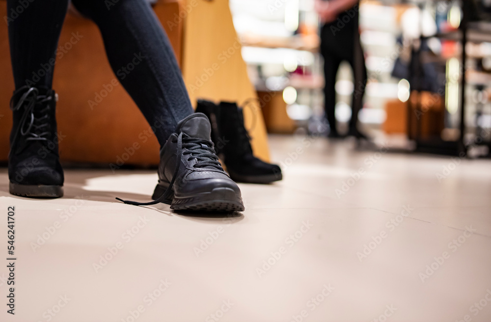 Naklejka premium Woman trying new black shoes sitting in a shop