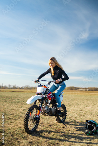 Attractive blonde girl on motocross. Sporty woman biker at motobike. Countryside, country road. sunset, female motorcycle rider, motorbike rider travel the world, girl resting, freedom lifestyle