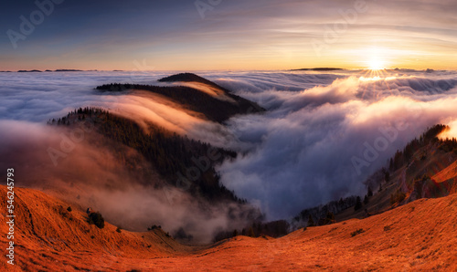 Mountain landscape above clouds at sunset in Slovakia with forest and sun