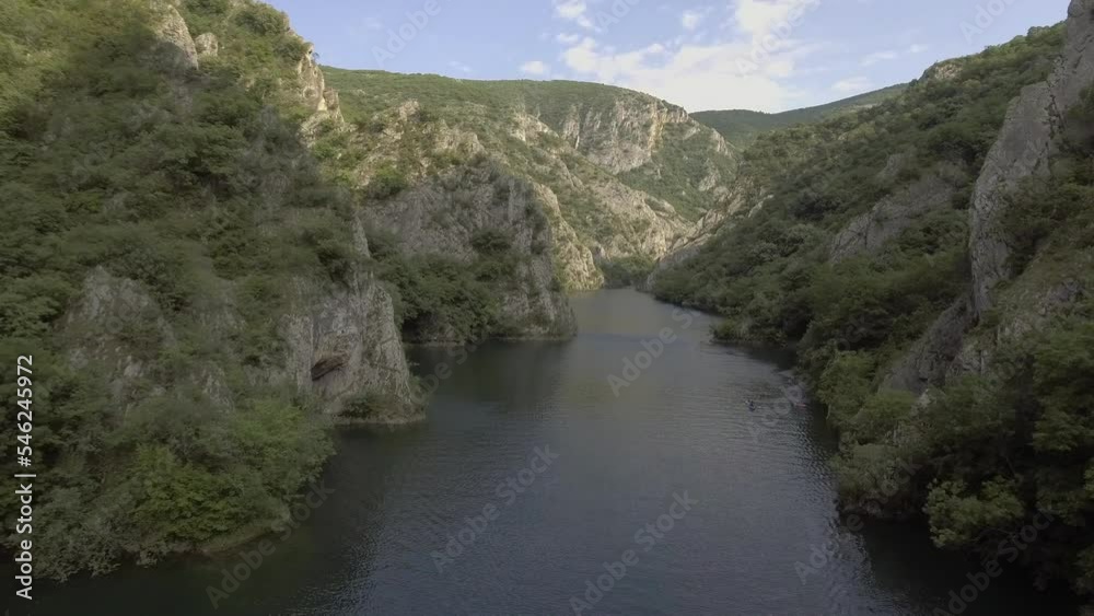 Aerial shot of a kayaker paddling through a mountain valley Aerial shot of a kayaker paddling through a mountain valley