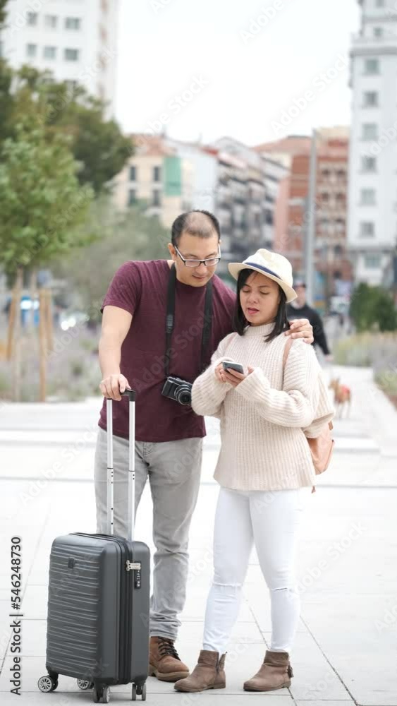 Multiracial couple of tourists consulting a city guide in their smartphone. Sightseeing in Madrid, Spain. Multiracial couple of tourists consulting a city guide in their smartphone. Sightseeing in Madrid, Spain.