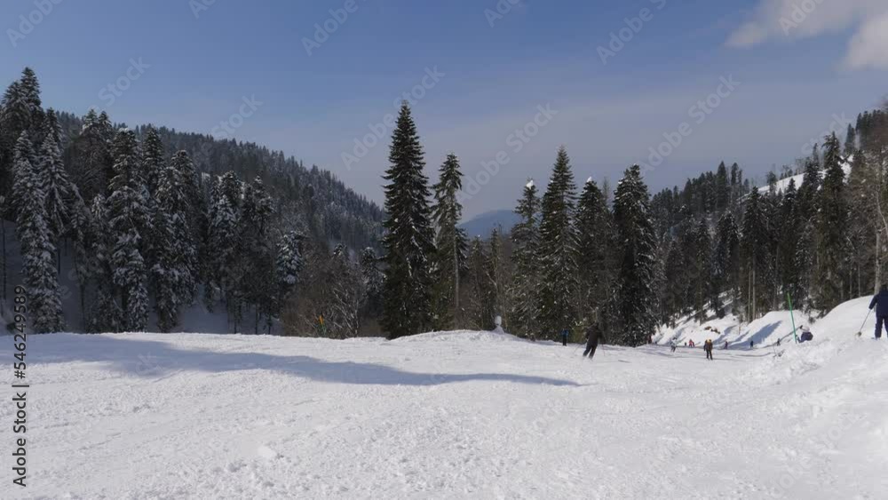 Skiers and snowboarders skiing slide down snowy slope mountainside in mountains at ski resort in winter sunny day. Active healthy sport recreation in mountains. Picturesque mountainside landscape Skiers and snowboarders skiing slide down snowy slope mountainside in mountains at ski resort in winter sunny day. Active healthy sport recreation in mountains. Picturesque mountainside landscape