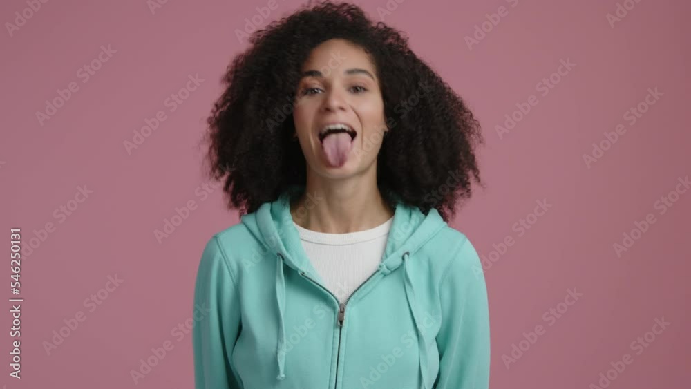 Close up view of a mixed race woman making silly facial expression. Portrait of young, playful lady showing a tongue. High quality 4k footage
