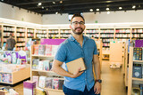 Caucasian man visiting his local bookstore and buying a couple of books with a smile