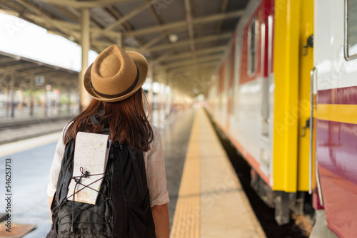 Young asian woman traveler backpack holding a map at the train station. Backpacker female wear hat and face medical mask at the railway. The concept of a woman traveling alone. Lady traveler tourist.