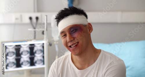 Male patient with bandaged head and bruised face acting crazy in hospital ward photo