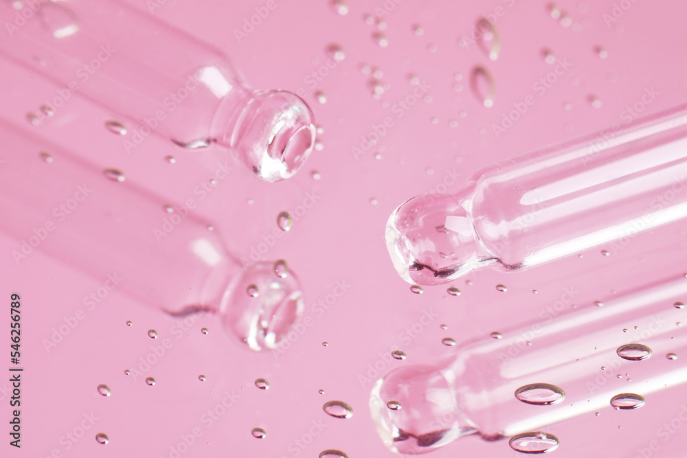 Pipettes near serum drops on beautiful mirror, closeup. Toned in pink Pipettes near serum drops on beautiful mirror, closeup. Toned in pink