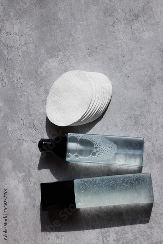 Luxury cosmetic products and cotton pads on grey table, flat lay. Space for text