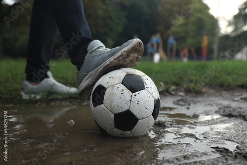 Man with dirty soccer ball in puddle outdoors, closeup © New Africa