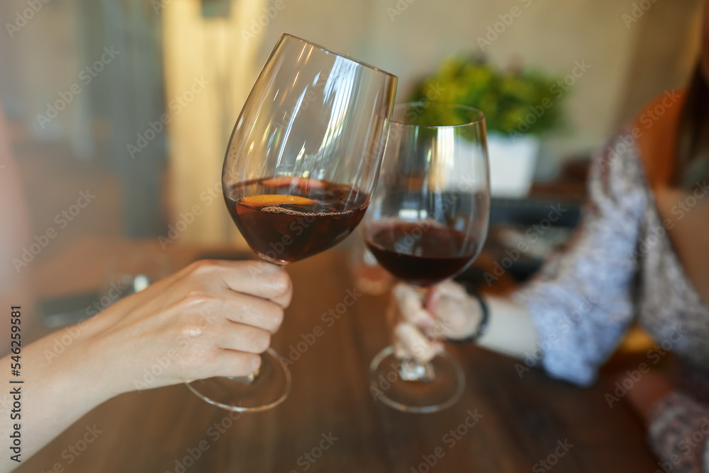 Women clink glasses of red wine.