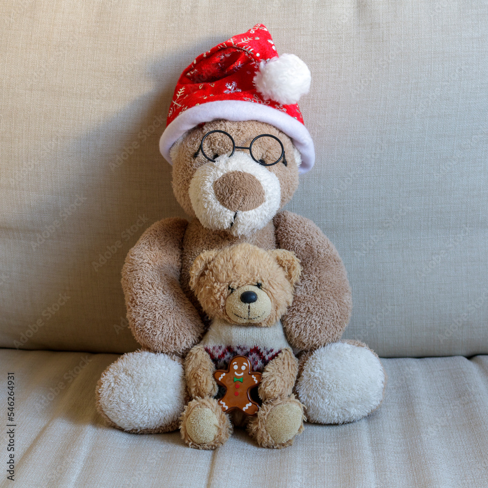 Big and small teddy bears sitting on a sofa at Christmas time